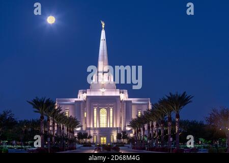 The Harvest Moon low in the sky over the Latter Day Saints temple in Gilbert, Arizona shortly before sunrise. Stock Photo