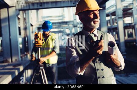 Two satisfied engineers talking at building site with construction structure in background Stock Photo