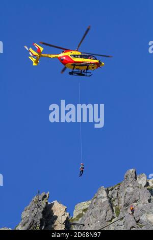 CHAMROUSSE, FRANCE, September 18, 2020 : A group of Civil Security rescuers are training to recover a wounded man in the mountains under an helicopter Stock Photo