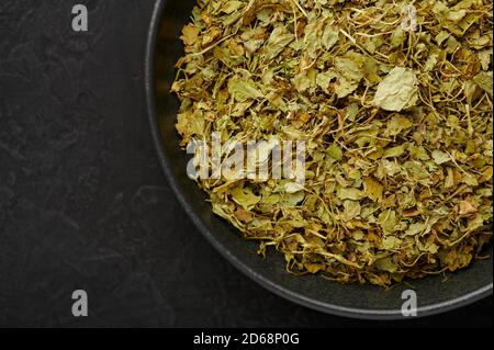 Dry Kasuri Methi or Fenugreek in black bowl on dark slate table top. Dried Fenugreek is is the popular seasoning of many asian cuisines. Stock Photo