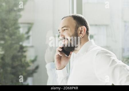 Businessman standing near the window and talking on phone Stock Photo