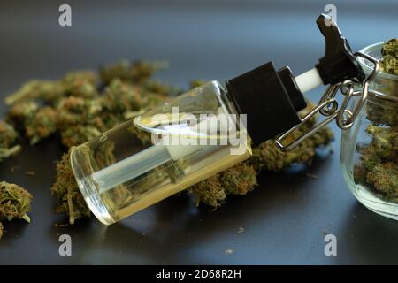 CBD extract in bottle. Hemp organic oil for medical use. Cannabidiol and THC. Marijuana buds on desk close-up Stock Photo