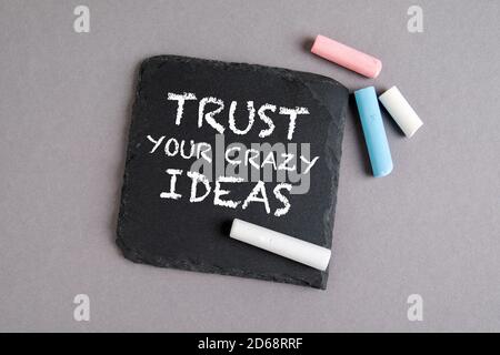 TRUST YOUR CRAZY IDEAS. Text on a stone surface. Chalk on a gray background Stock Photo