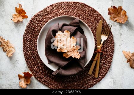 Top view of decorated table setting dish with fallen leaf. Thanksgiving or Autumn festive dinner concept. Stock Photo