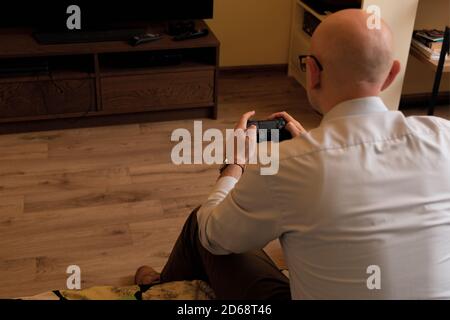 Back view of gamer male playing video games. holding gamepad controller late at night in the living room Stock Photo