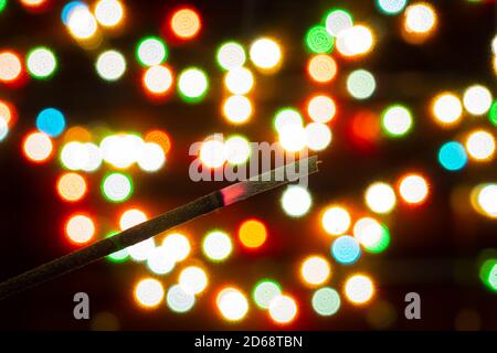 Incense stick on the background of bokeh of colorful lights of garlands Stock Photo