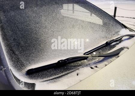 Car windshield in the snow in the evening under the light of a lantern Stock Photo