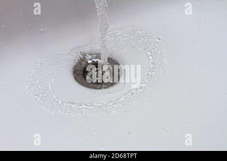 Water running into sink drain closeup, drop of water falling in slow motion Stock Photo