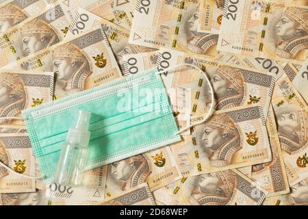 Lots of 200 zloty bills with a medical protective mask on them. Conceptual image about the stability of the economy in Poland. Stock Photo