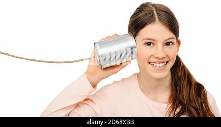 Positive girl with a tin can near the ear, playing the phone. I hear you well, child isolated on white Stock Photo