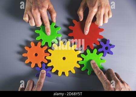 business development, teamwork and collaboration concept - people connecting gears. top view Stock Photo