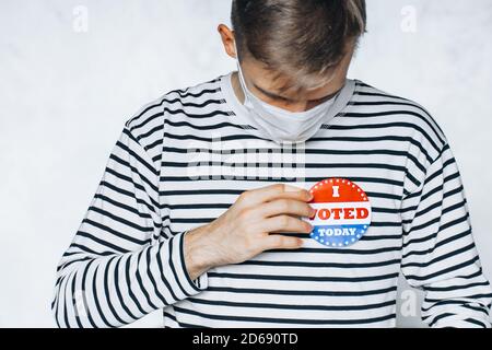 young man in face medical mask wearing on shirt I VOTED TODAY pin. election day on coronavirus pandemic. November elections in the United States 2020. Stock Photo