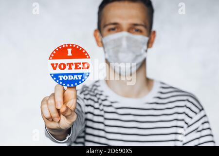 Blurred portrait of man in face medical mask holding I VOTED TODAY sticker. election day on covid pandemic. November elections in the United States 20 Stock Photo