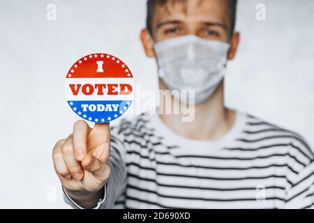 Blurred portrait of man in face medical mask holding I VOTED TODAY sticker. election day on covid pandemic. November elections in the United States 20 Stock Photo