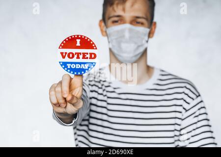 young man citizen of America holding I voted today sticker button. November elections in the United States 2020. Copy Space. isolated on white blurred Stock Photo