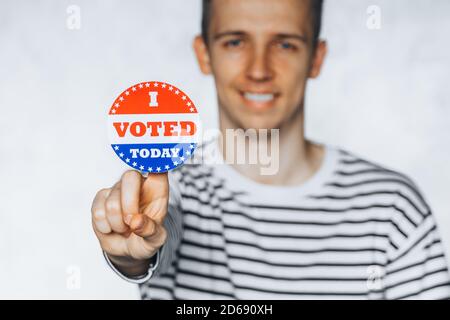 young man citizen of America holding I voted today sticker button. November elections in the United States 2020. Copy Space. isolated on white blurred Stock Photo