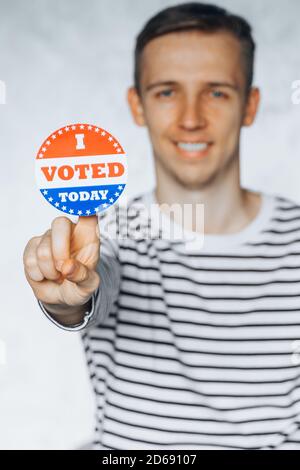 young man citizen of America holding I voted today sticker button. November elections in the United States 2020. Copy Space. isolated on white blurred Stock Photo