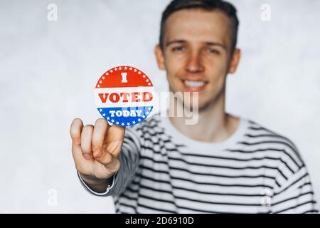 young man citizen of America holding I voted today sticker button. November elections in the United States 2020. Copy Space. isolated on white blurred Stock Photo