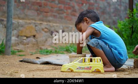 An Indian Village cute boy playing with his old car toy Stock Photo