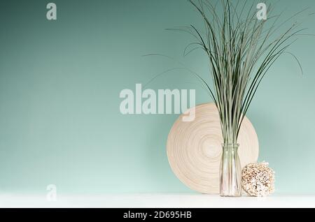Elegant interior with natural beige decoration in eco style -  decorative round sheaf of twigs, bamboo plate, bouquet of cane in bottle on green mint Stock Photo