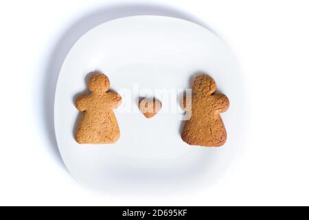 Two gingerbread men on a plate with little heart, isolated on a white. Stock Photo