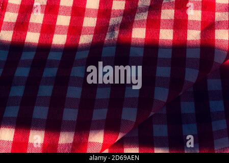 The checkered tablecloth on a table. Texture of white fabric in a red cell. Stock Photo