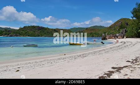 Curieuse Island, Seychelles - 09/25/2018: Boats docking on tropical beach in Laraie Bay on protected island Curieuse with turquoise colored water. Stock Photo