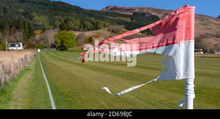 A windswept and torn corner flag at the Kirkton ground, the old home of Kinlochshiel Shinty Club in the west of Scotland. Stock Photo