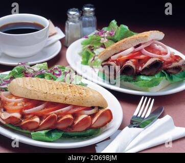 Two sandwiches with fresh vegetables, ham, tomato and onion in ciabatta bread served with cup of coffee Stock Photo