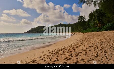 Tourists enjoying their holidays (swimming, sunbathing, relaxing) on popular beach Anse Intendance with tropical forest on the west coast of Mahe. Stock Photo