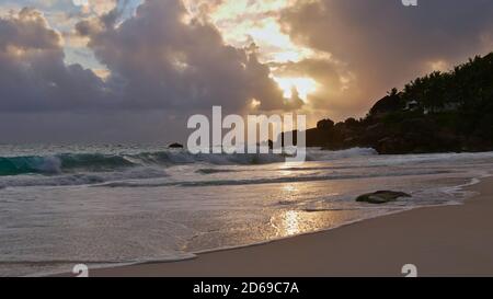 Beautiful sunset on tropical beach Anse Intendance on the west coast of Mahe island, Seychelles with granite rock formations and sun shining through. Stock Photo