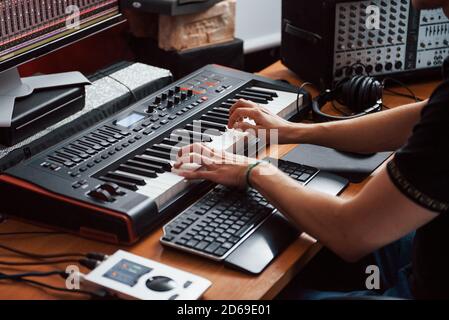 Playing midi keyboard. Sound engineer working and mixing music indoors in the studio Stock Photo