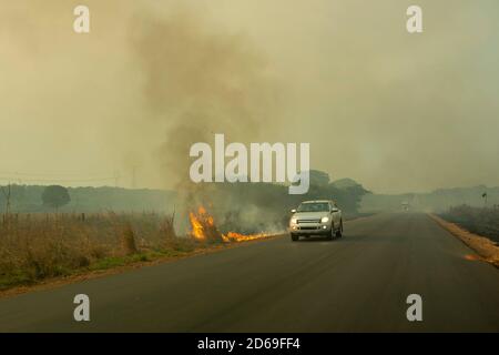 Fire and smoke on BR 163 road on Amazon during dry season and blurred car driving fast near the flames. Para state, Brazil. Concept of environment. Stock Photo