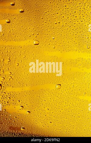 Close up view of cold drops on the glass of beer background. Texture of cooling alcohol drink with macro bubbles on the glass wall. Fizzing or floating up to top of surface. Golden colored. Stock Photo