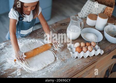 Cute kid in white chef uniform preparing food on the kitchen Stock Photo