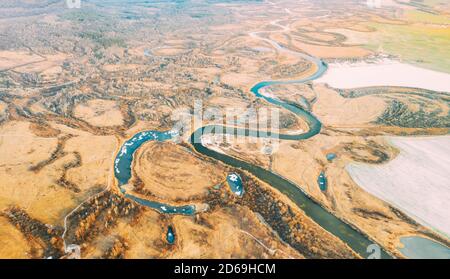 Aerial View Of Dry Grass And Partly Frozen Curved River Landscape In Late Autumn Day. Fields Are Covered With Snow Stock Photo