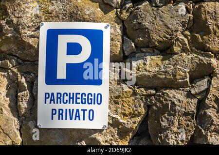 Parcheggio Privato, Blue and white Private Parking sign in Italian language hanging on a stone wall. Liguria, Italy, Europe Stock Photo