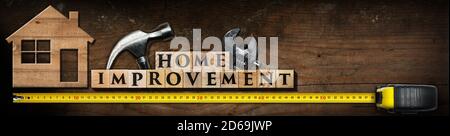 Text Home Improvement, made of wooden blocks on a wooden table with work tools (hammer, adjustable wrench and yellow tape measure) and model house. Stock Photo