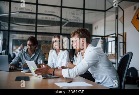 Sits by the table with laptops. Young business people in formal clothes working in the office Stock Photo