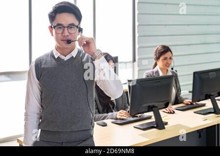 Portrait of Young adult friendly and confidence operator man with headsets and his team working in a call center as customer service and technical