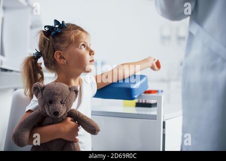 Preparation for blood sampling. Little girl with her toy in hands is in the clinic Stock Photo