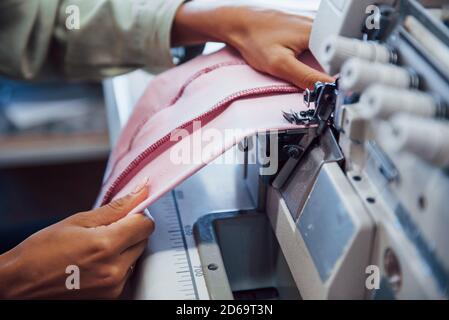 Detailed view of dressmaker woman sews clothes on sewing machine in factory Stock Photo