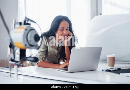 Using laptop. Beautiful female worker is in the sewing factory Stock Photo
