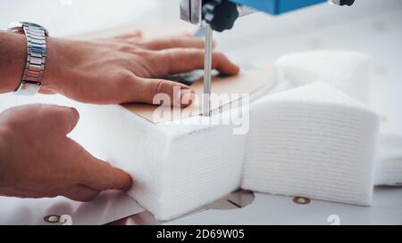 Detailed view of dressmaker woman sews clothes on sewing machine in factory Stock Photo
