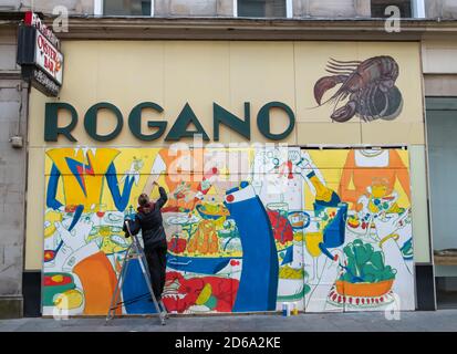 Glasgow, Scotland, UK. 15th October, 2020. UK Weather. Glasgow based freelance illustrator and cartoonist Ida Henrich at work on a new mural entitled Dinner Party on the outside of the Rogano restaurant. Credit: Skully/Alamy Live News Stock Photo
