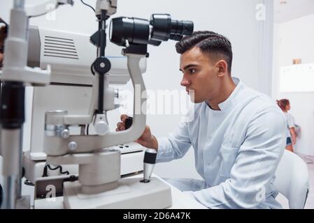 Oculist tests vision of patient by using special modern machine Stock Photo