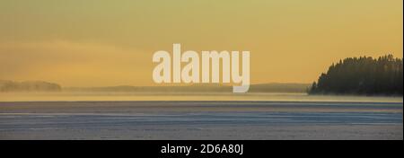 Misty half frozen lake at evening light at Winter , Finland Stock Photo