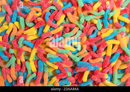 Sour candy gummy worms close up background. Covered in granulated sugar. Flat lay top view from above. Stock Photo