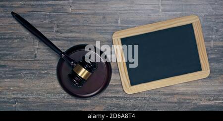 Judge or auction gavel beside a chalkboard on wooden background. Banner size with copy space. Stock Photo