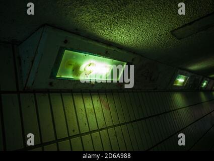Spooky green lighting in a run down An urban pedestrian underpass. Stock Photo